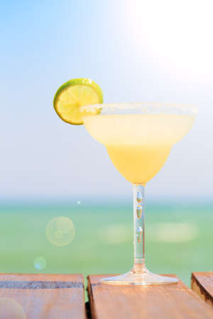 Margarita cocktail on the wooden pier. Concept of classic drink. Vacation background. Vertical, direct sun bokeh, zero level shoot. Shallow DOFの写真素材