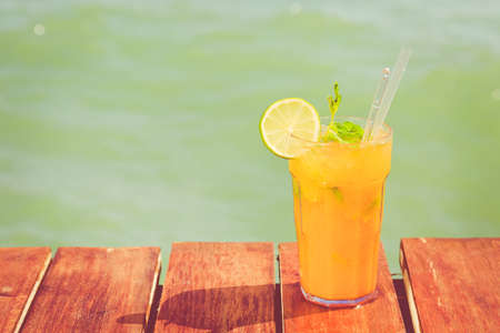 Mango mojito on the wooden pier. Concept of luxury tropical vacation. Classic cocktail. Toned, horizontal,の写真素材
