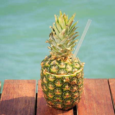 Exotic cocktail in the pineapple. Sea pier. Concept of luxury vacation. Beach party. Upscale resort...
