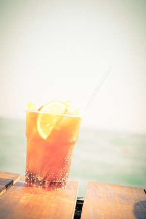 Concept of luxury vacation. Cuba Libre cocktail on the pier. Long island ice tea cocktail on the pier. Tropical vacation background. Right side angle. Clear blue sky. Vertical, tonedの写真素材
