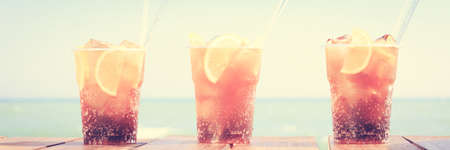 Concept of luxury vacation. Cuba Libre cocktail on the pier. Long island ice tea cocktail on the pier. Tropical vacation background. Beach party. Clear blue sky. Horizontal, banner, tonedの写真素材