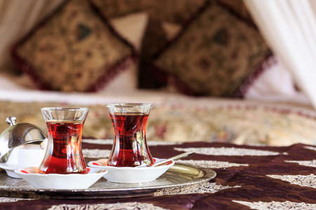 Two turkish tea cups and turkish delight with oriental canopy bed at the background. Silver tray. Romantic concept. Valentines background. Arabian nights ambiance. Horizontal, cups on the left sideの写真素材