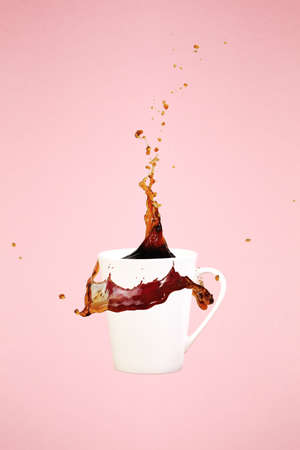 Coffee concept. Minimal art. Solid background. Coffee splashes. Levitating mug. Pink background. Vertical, straight cupの写真素材