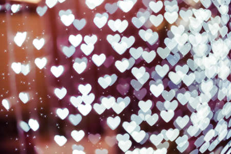 Heart shaped holiday blurred bokeh background with sparkles. Valentine background. Christmas background. Horizontal.の写真素材