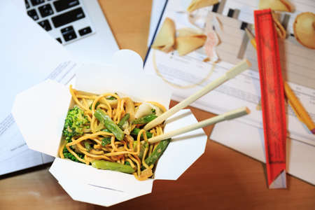 Chinese food box on the office desk. Eating at the office. Overtime work concept. Top view. Horizontalの写真素材