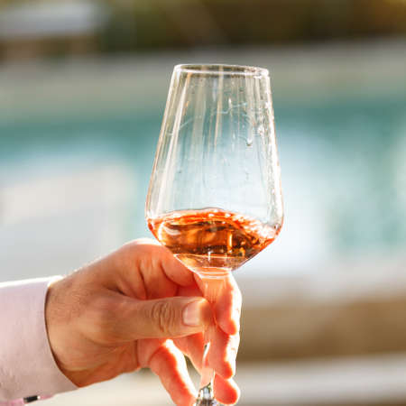Swirling glass of rose wine at outdoor wine tasting. Concept of rose wine.  Squareの写真素材