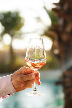 Swirling glass of rose wine at outdoor wine tasting. Concept of rose wine.  Verticalの写真素材