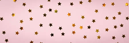 Golden star sprinkles on pink. Festive holiday background. Celebration concept. Top view, flat lay....