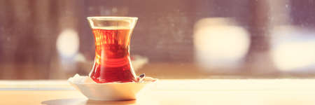Hot turkish tea outdoors near glass wall. Turkish tea and traditional turkish culture concept. Horizontal, banner format. Toned image, warm sunset lightの写真素材
