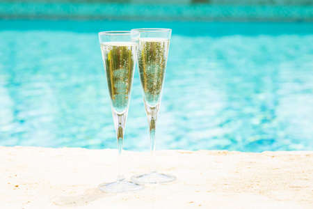 Two glasses of prosecco   at the edge of a resort pool. Concept of luxury vacation. Outdoor pool background. Horizontalの写真素材