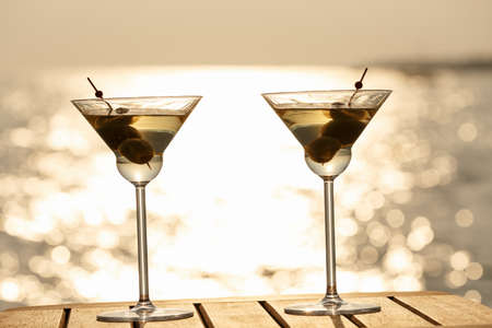 Two martini cocktails at the wooden pier at sunset. Luxury resort vacation concept. Festive relax getaway background. Horizontalの写真素材