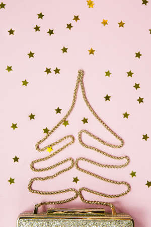 Festive evening golden clutch with star sprinkles on pink. Holiday and celebration background. Luxury accessories and party concept. Christmas and New Year Celebration. Verticalの写真素材