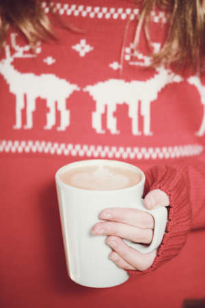 Girl holding coffee. Christmas holiday background, direct light. Verticalの写真素材