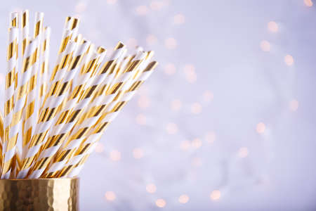 Gold and white paper straws in the golden glass. Christmas concept. Festive holiday party background. Horizontalの写真素材