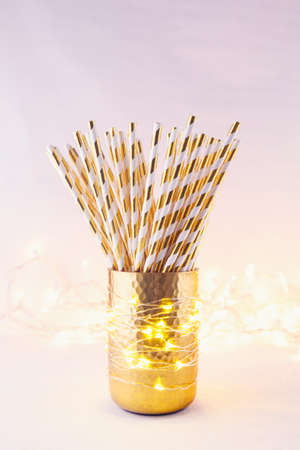 Gold and white paper straws in the golden glass. Christmas concept. Festive holiday party background. Verticalの写真素材