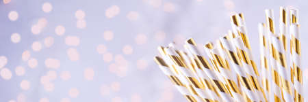 Gold and white paper straws in the golden glass. Christmas concept. Festive holiday party background. Horizontal, banner formatの写真素材
