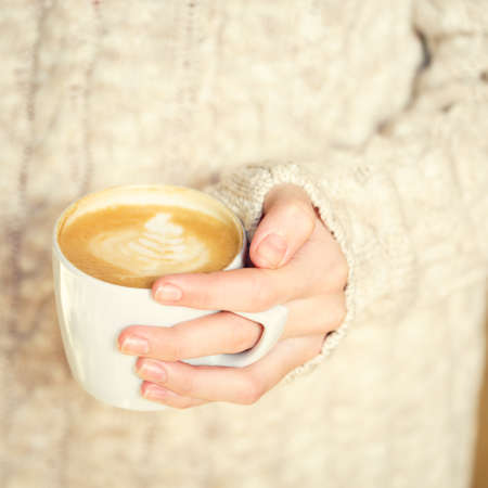 Girl holding a cup of coffee or hot chocolate or chai tea latte. Quiet hygge time concept. Warm tone.の写真素材