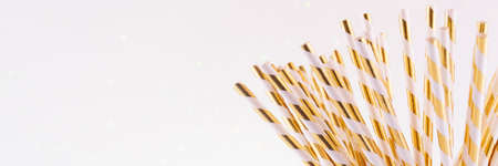Gold and white paper straws in the golden glass. Christmas concept. Festive holiday party background. Horizontal, banner formatの写真素材