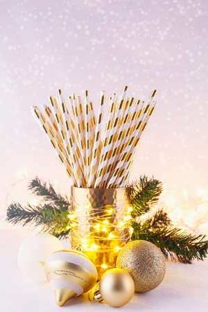 Gold and white paper straws in the golden glass. Christmas concept. Festive holiday party background. Verticalの写真素材