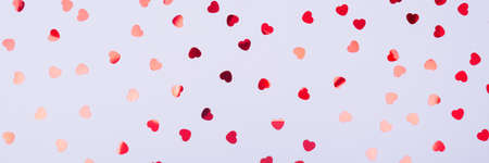 Grey background with red glitter heart confetti. Valentine day concept. Trendy minimalistic flat lay...