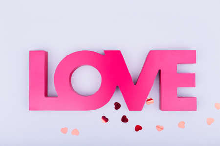 Red sign LOVE and glitter heart confetti. Valentine day concept. Trendy minimalistic flat lay design background. Horizontalの写真素材