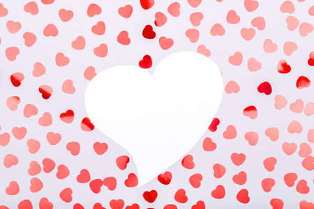 White heart with glitter heart confetti. Valentine day concept. Trendy minimalistic flat lay design...