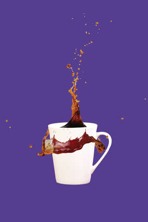 Levitating coffee mug with splashes. Coffee concept. Minimal art trend. Solid ultra violet background. Vertical, straight cupの写真素材
