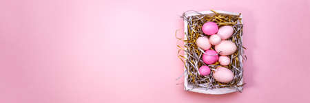Eggs in a white tray. Creative Easter concept. Modern solid pink background. Horizontal, banner formatの写真素材