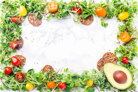 Sprouted baby greens frame with cherry tomatoes, seeds and nuts crackers and avocado. Superfood snack concept. Horizontalの写真素材