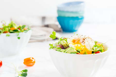 Mixed baby greens and cherry tomatoes salad with avocado and poached egg in bowl. Superfood snack concept. Horizontalの写真素材