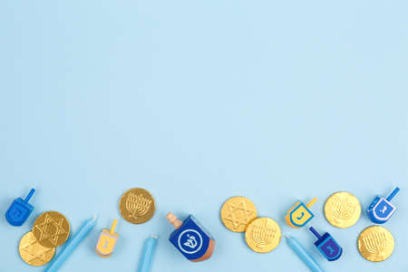 Blue background with multicolor dreidels, menora candles and chocolate coins. Hanukkah and judaic...