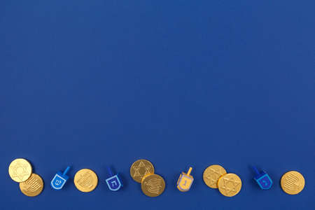 Dark blue background with multicolor dreidels and chocolate coins. Hanukkah and judaic holiday...