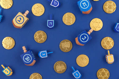 Dark blue background with multicolor dreidels and chocolate coins. Hanukkah and judaic holiday...