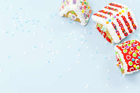 Gingerbread houses and snow sprinkles on the blue background. Christmas kids treats concept. Horizontalの写真素材