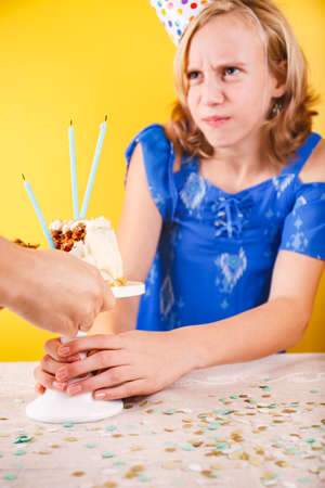 Teenage girl trying to keep birthday cake. One person party. Concept of birthday party, messthetics and misconduct. Verticalの写真素材