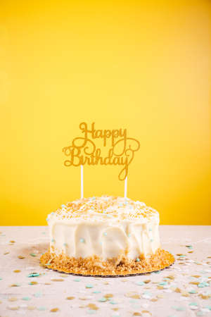 Birthday cake with golden topper. Birthday party celebration concept. Vertical, bold yellow...