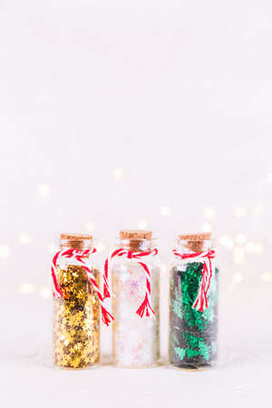 Glass bottles with glitter confetti on white background with bokeh lights. Holiday Christmas and New Year background. Verticalの写真素材