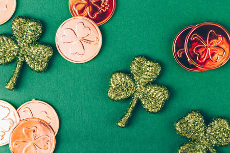 Glitter shamrocks and golden coins on green paper background. St Patricks day symbol. Irish National holiday concept. Horizontalの写真素材