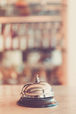 Ring bell for staff calling on the stand. Reception and bar background. Holiday and travel concept. Vertical, warm toningの写真素材