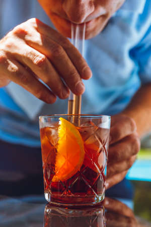 Man drinking negroni cocktail at the resort bar or suite patio. Luxury resort, vacation, room service concept. Verticalの写真素材