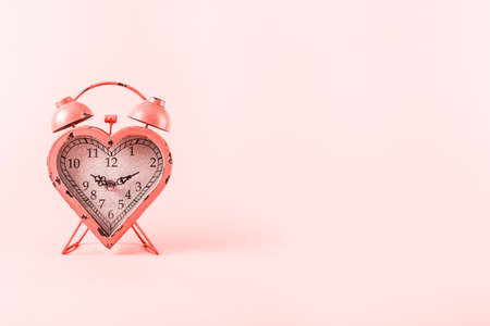 Heart shaped clock on pink background.  Valentines day and love infitity and duration concept. Horizontal. Living coral theme - color of the year 2019の写真素材