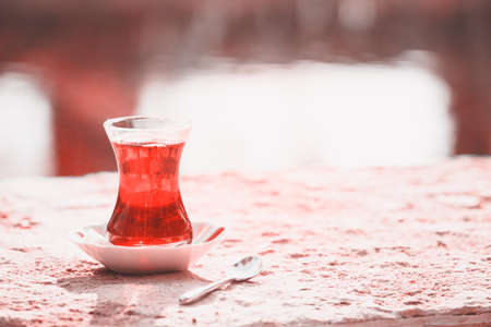 Hot turkish tea outdoors near water. Turkish tea and traditional turkish culture concept. Horizontal. Toned image. Living coral theme - color of the year 2019の写真素材