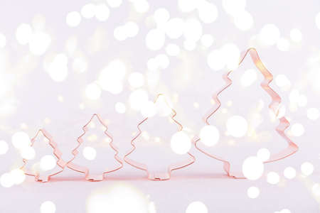 Row of Christmas Tree Copper cookie cutters on white sparkling background with bokeh lights. Holiday Christmas and New Year background. Horizontal, bright lights bokeh backgroundの写真素材