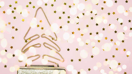 Festive evening golden clutch with star sprinkles on pink. Holiday and celebration background. Luxury accessories and party concept. Christmas and New Year Celebration. Horizontal, wide screen, bold light bokeh backgroundの写真素材