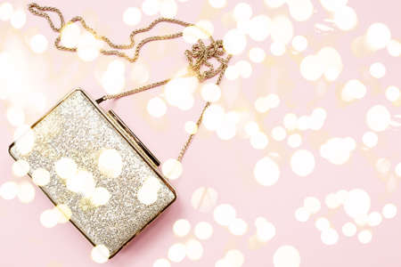 Festive evening golden clutch on pink. Holiday and celebration background. Luxury accessories and party concept. Horizontal, bold light bokeh backgroundの写真素材
