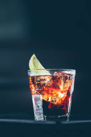 Cuba libre cocktail at the bar stand. Dark background. Verticalの写真素材