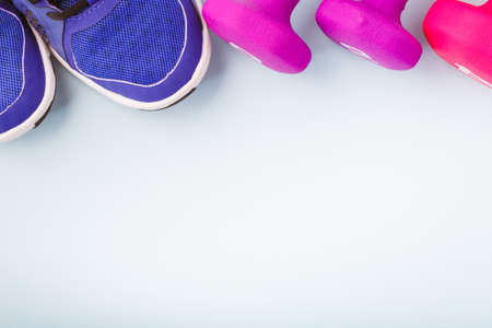 Sneakers and dumbbells on the solid backdrop. Keep fit athletic and healthy sports concept. Top viewの写真素材