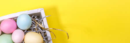 Multicolor eggs in a white tray. Creative Easter concept. Modern solid yellow background. Horizontal, wide screen banner formatの写真素材