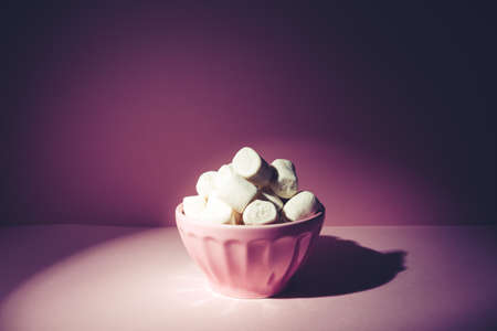 Pink bowl of giant marshmallows on pink backdrop with harsh shadowsの写真素材