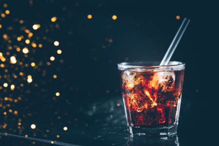 Cuba libre cocktail at the bar stand. Dark background. Horizontal. Festive holiday bokehの写真素材